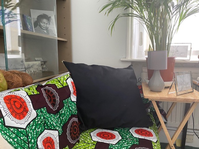 A photo of a room with a green and red patterned couch and black pillow